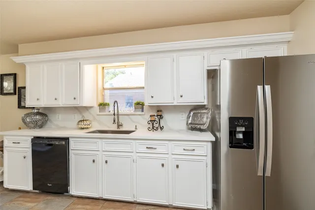 a kitchen with stainless steel appliances granite countertop a refrigerator sink and white cabinets