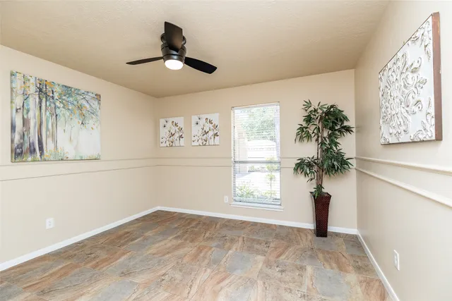 a view of empty room with window and ceiling fan