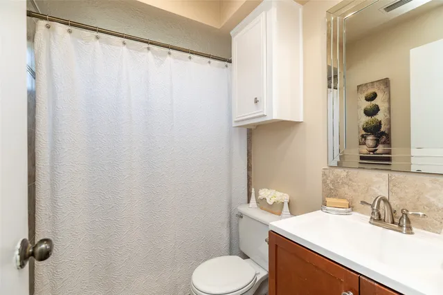 a bathroom with a granite countertop sink toilet and a mirror