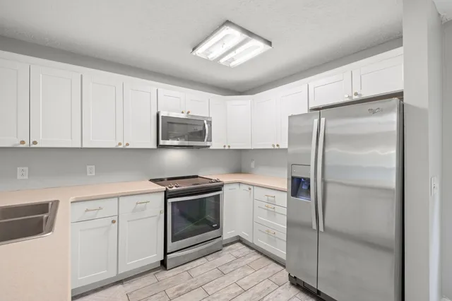 a kitchen with white cabinets and stainless steel appliances