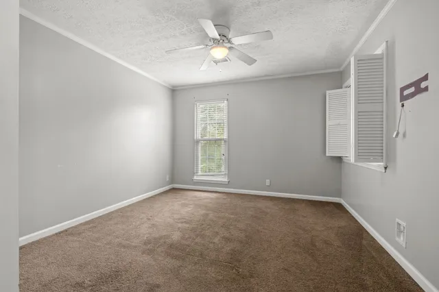 an empty room with windows and ceiling fan