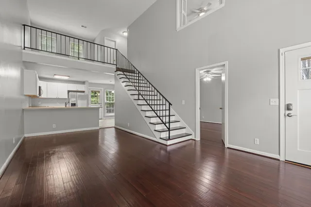 an empty room with wooden floor staircase and windows