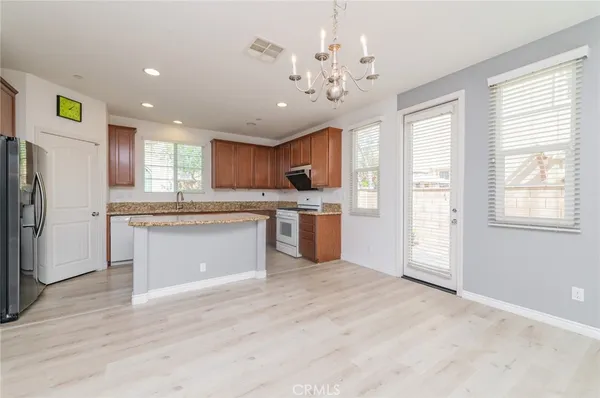 a large kitchen with kitchen island a sink stainless steel appliances cabinets and wooden floor