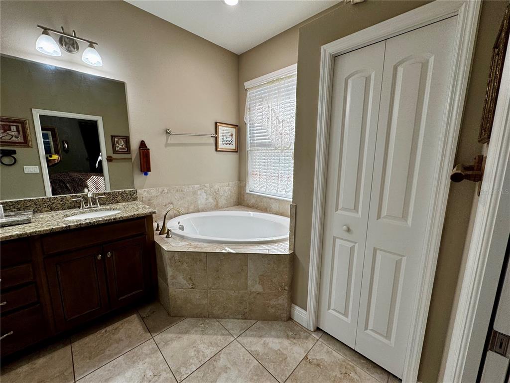 12419 Betony Court New Port Richey, FL 34654 - Photo 14 of 24 a bathroom with a granite countertop sink a toilet mirror and vanity