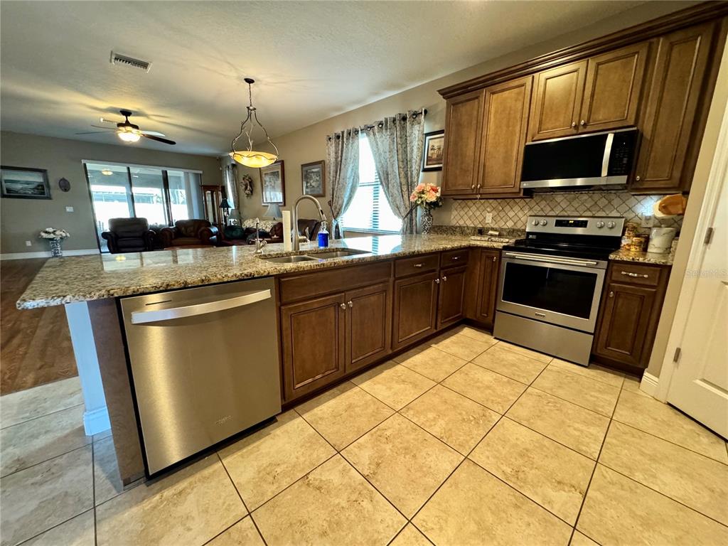 12419 Betony Court New Port Richey, FL 34654 - Photo 6 of 24 a kitchen with stainless steel appliances granite countertop a sink stove and microwave