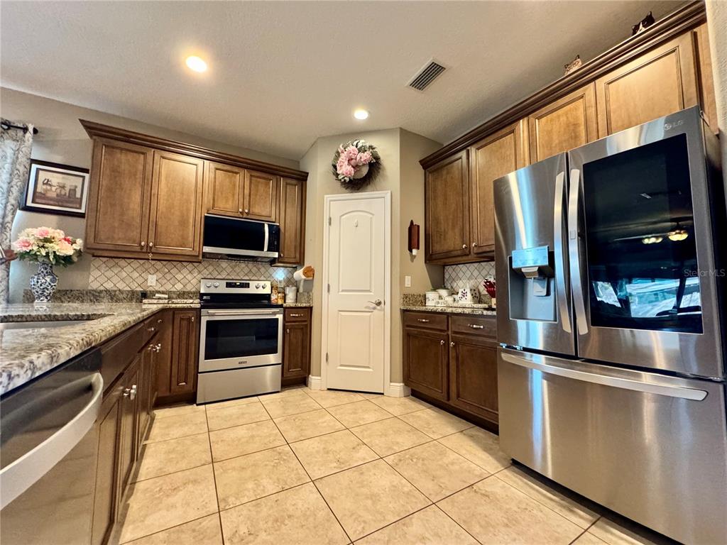 12419 Betony Court New Port Richey, FL 34654 - Photo 7 of 24 a kitchen with stainless steel appliances granite countertop a refrigerator stove and sink