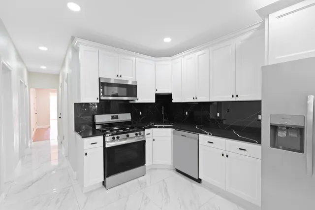 a kitchen with granite countertop white cabinets and stainless steel appliances