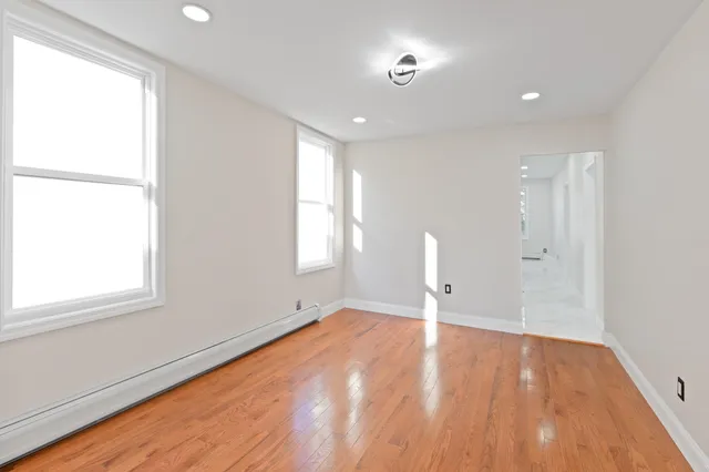 an empty room with wooden floor and windows