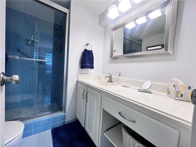 a bathroom with a sink a toilet a mirror and shower