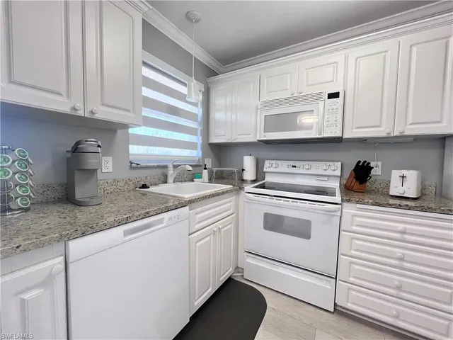 a kitchen with granite countertop white cabinets and white appliances