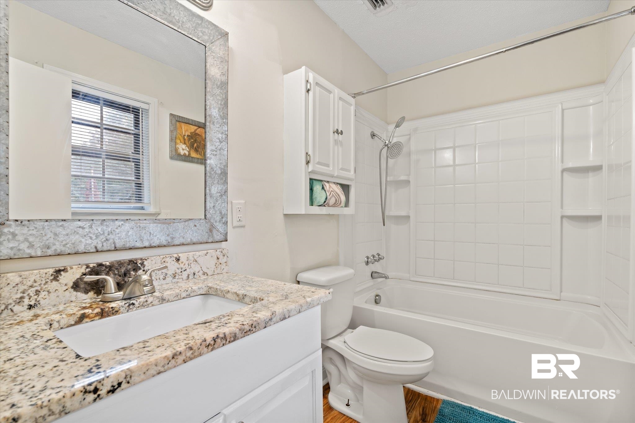 9445 Howells Ferry Road Semmes, AL 36575 - Photo 13 of 20 Full bathroom featuring vanity, a textured ceiling, tub / shower combination, hardwood / wood-style floors, and toilet