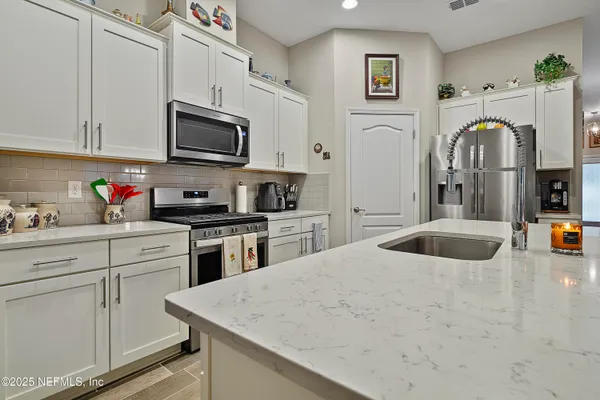 a kitchen with stainless steel appliances granite countertop a sink a stove and a refrigerator