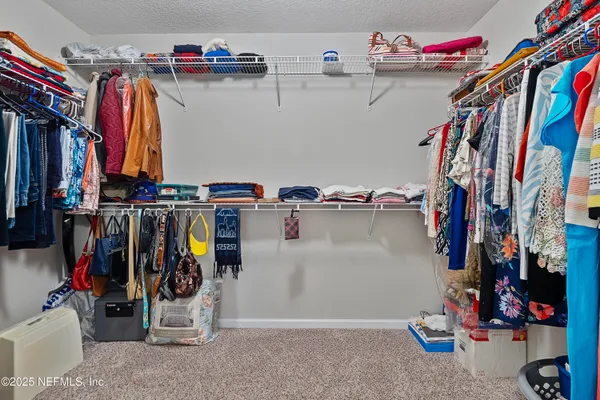 a view of walk in closet with clothes and shoes