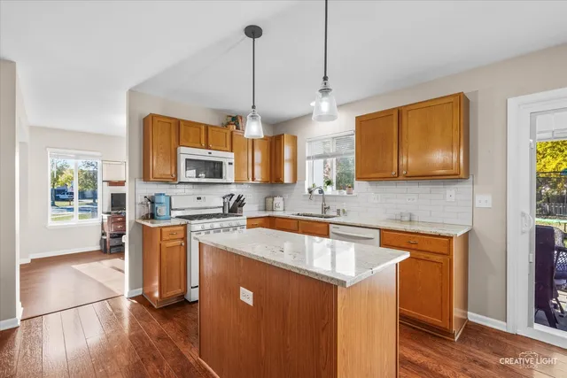 a kitchen with stainless steel appliances granite countertop a sink a stove and a wooden floors