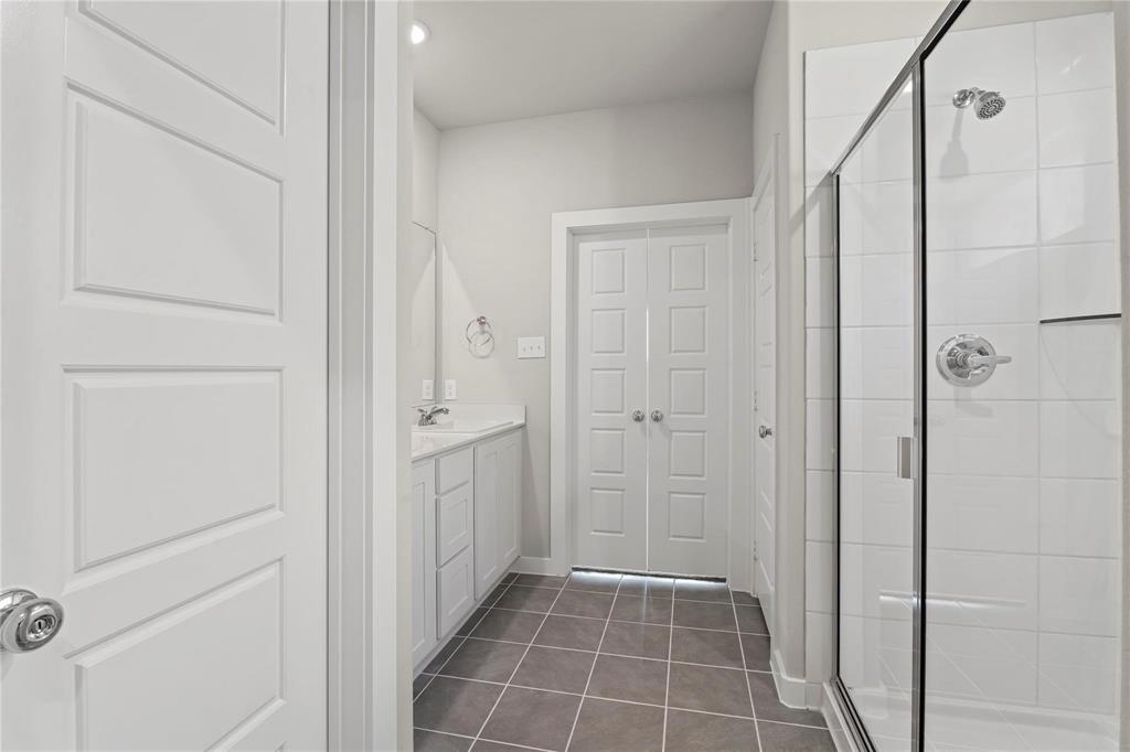 507 Avocet Road Princeton, TX 75407 - Photo 24 of 31 Modern bathroom featuring a glass-enclosed shower with subway tile, white vanity with integrated sink, and gray tiled flooring