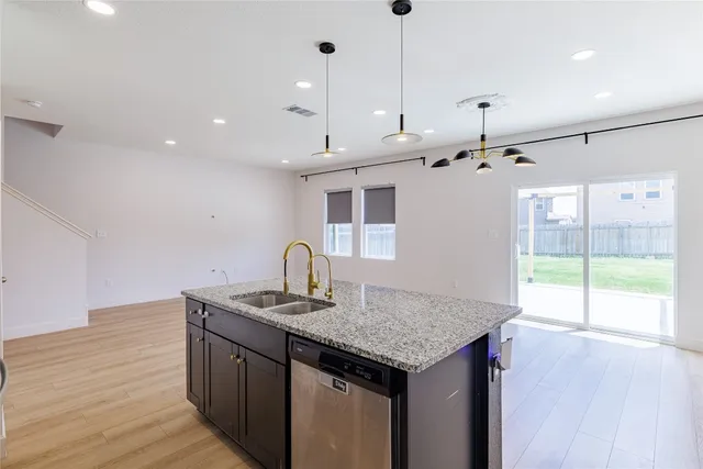 a kitchen with kitchen island granite countertop a sink and a wooden floor