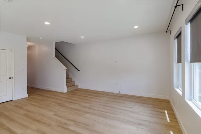 a view of an empty room with wooden floor and stairs
