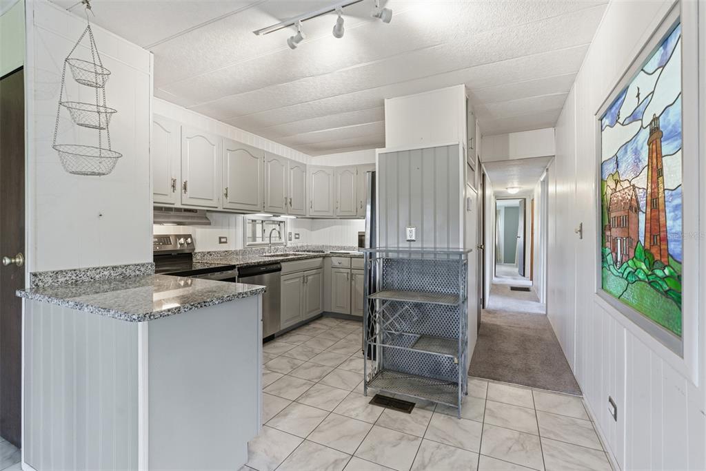 6147 Ridgewood Drive Zephyrhills, FL 33542 - Photo 5 of 21 a kitchen with stainless steel appliances granite countertop a refrigerator a sink a stove and white cabinets