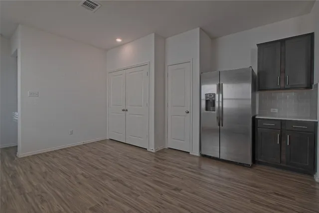 a view of an empty room with wooden floor kitchen and a window