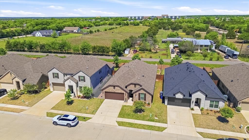 813 Mildren Lane Fate, TX 75087 - Photo 23 of 32 Front aerial view of the home showing the new Worthy Fate High School being constructed in the background with an expected opening in August of 2027! Current planning would allow the school to open with freshmen and sophomores and grow into a 9-12th grade school by 2030. Also notice the feeder road construction to the right (yellow backhoe) which we believe will connect Prince to FM 2642 .. right in front of the new HS!