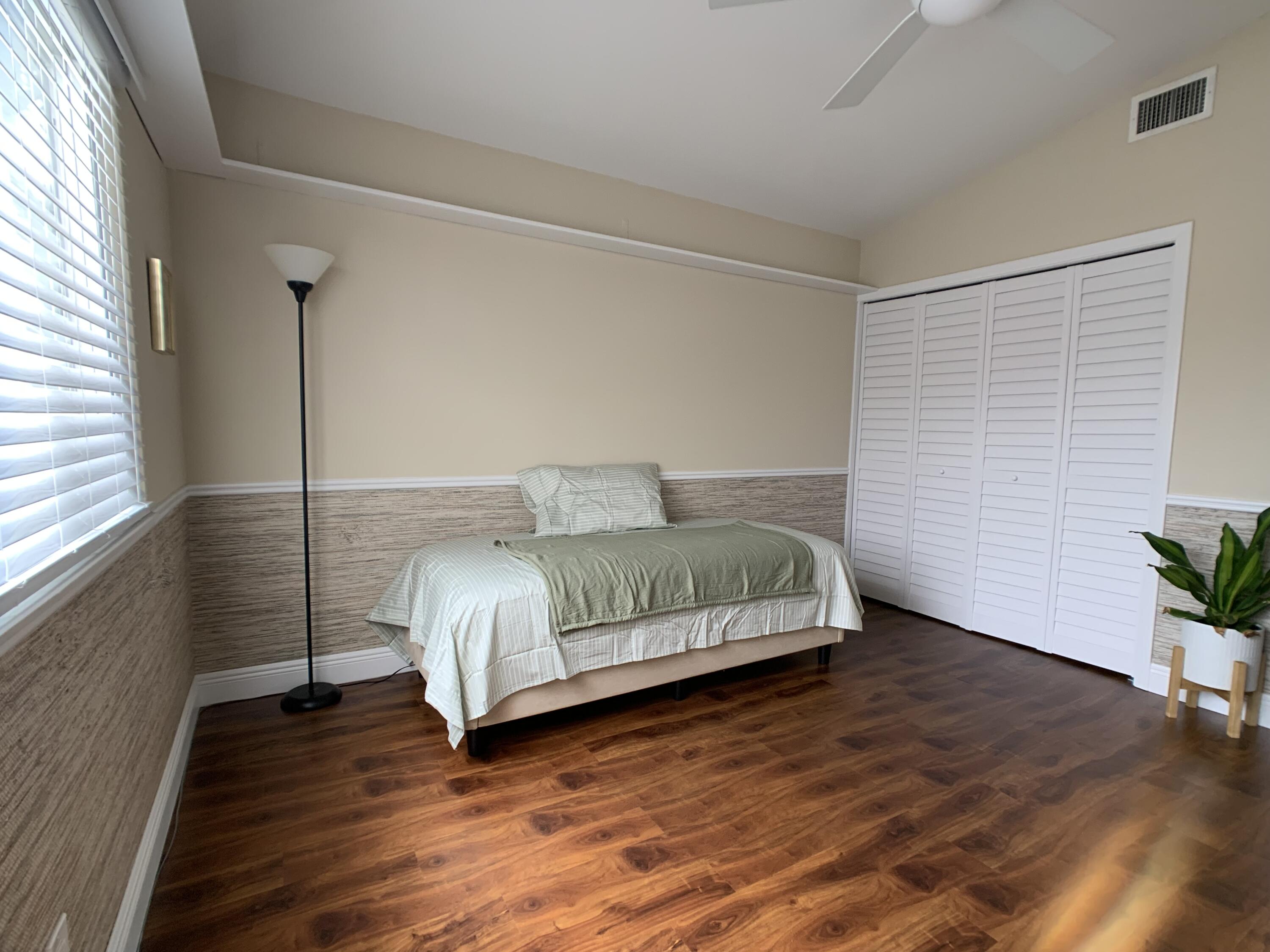 10465 Mateo Court Boca Raton, FL 33498 - Photo 17 of 36 a bedroom with a bed and wooden floor