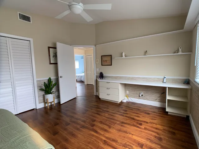 a view of an empty room and kitchen with wooden floor