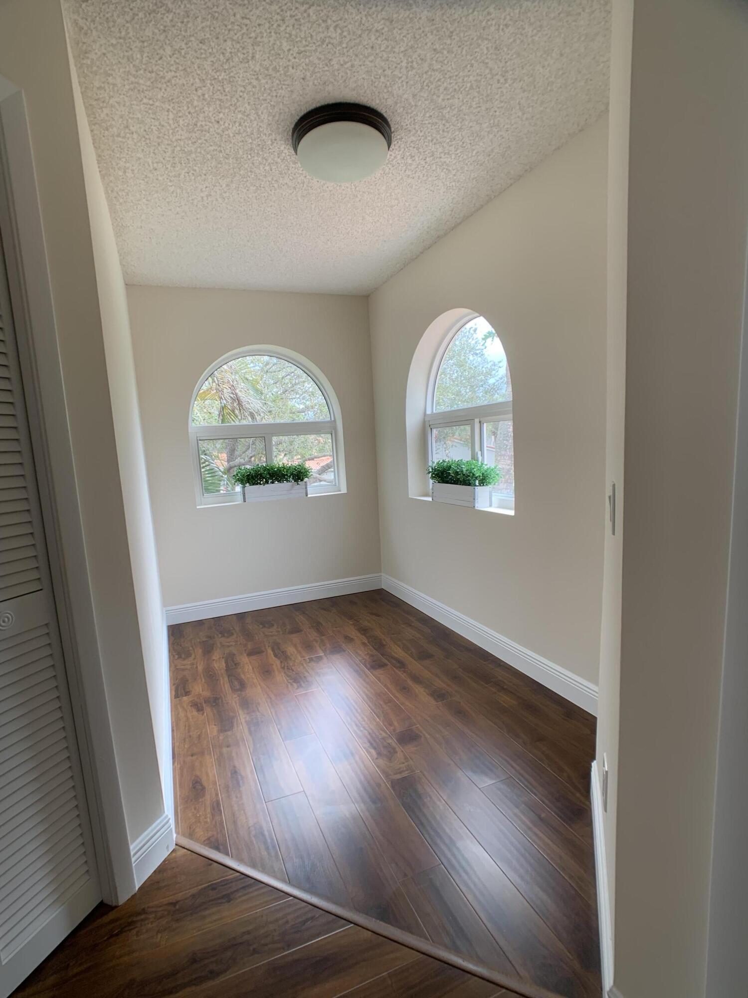 10465 Mateo Court Boca Raton, FL 33498 - Photo 21 of 36 an empty room with wooden floor and windows