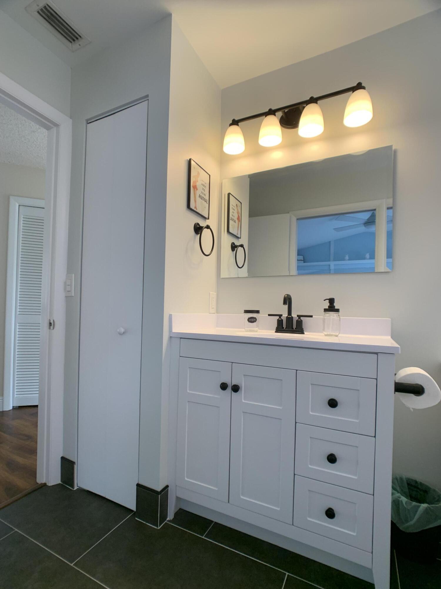 10465 Mateo Court Boca Raton, FL 33498 - Photo 25 of 36 a bathroom with a sink vanity and mirror