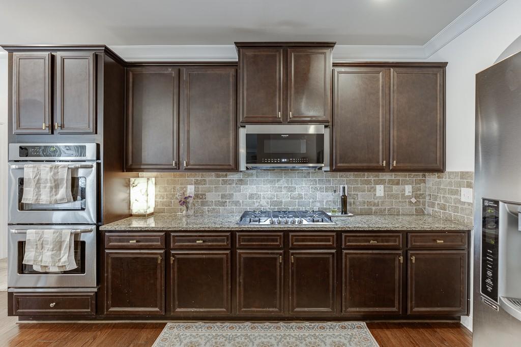 2906 Jones Phillips Road Dacula, GA 30019 - Photo 21 of 53 a kitchen with granite countertop stainless steel appliances and wooden cabinets