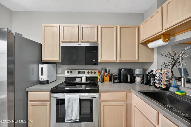 a kitchen with stainless steel appliances granite countertop a sink a stove and a refrigerator
