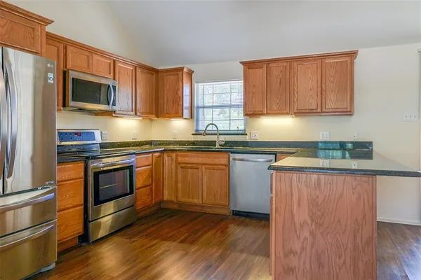 a kitchen with stainless steel appliances granite countertop a stove a sink and a microwave