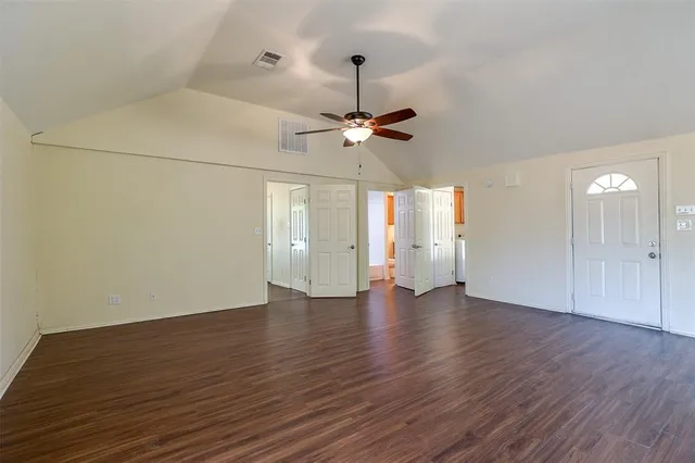 a view of an empty room with window and wooden floor