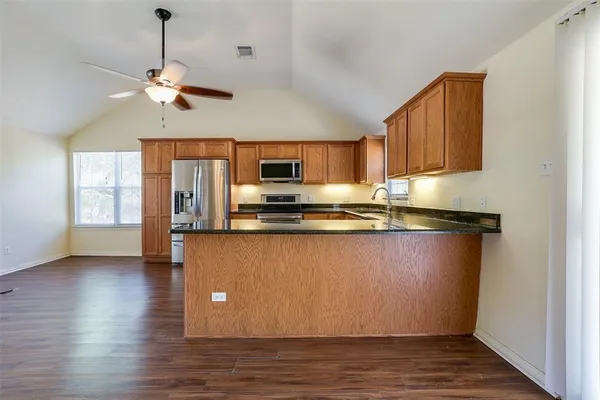 a living room with stainless steel appliances granite countertop furniture and a wooden floor
