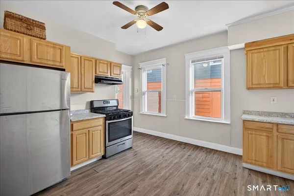 a kitchen with stainless steel appliances granite countertop a refrigerator a stove a sink dishwasher a microwave oven with cabinets and wooden floor