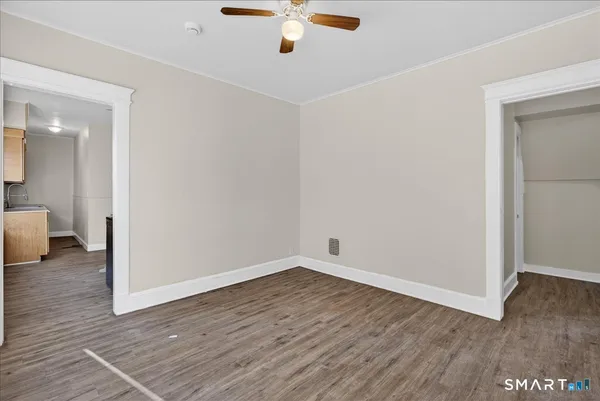 an empty room with wooden floor and a ceiling fan