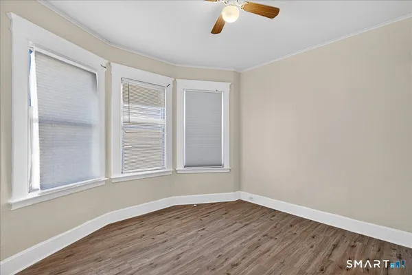 a view of an empty room with wooden floor and a window