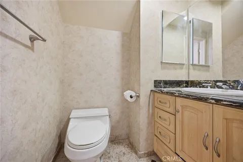 a bathroom with a granite countertop toilet and a sink