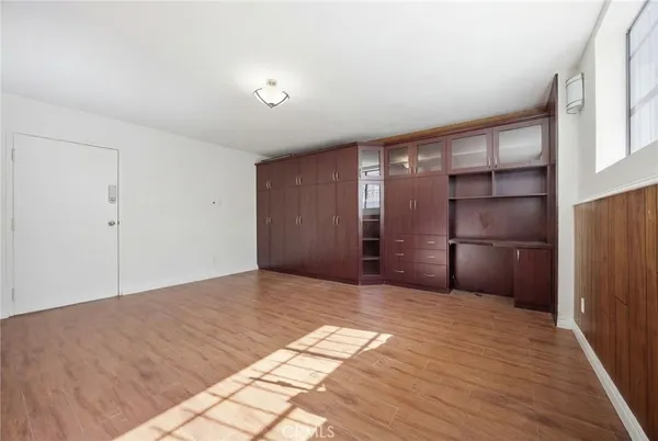a view of an empty room with wooden floor and closet