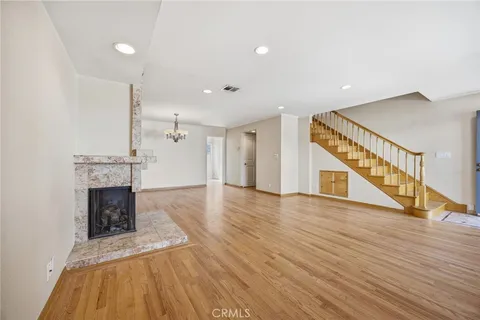 a view of an empty room with wooden floor fireplace and a window