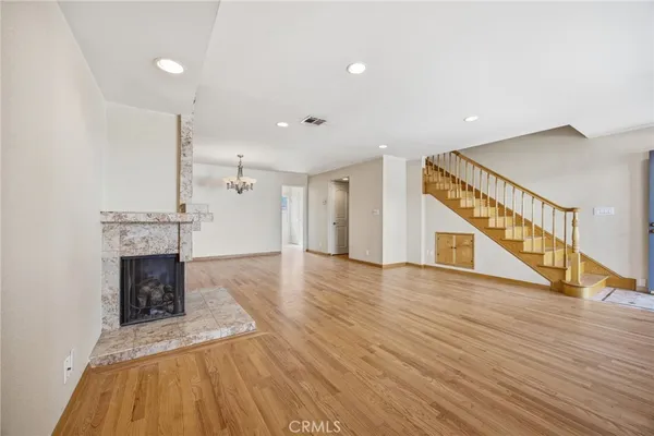 a view of an empty room with wooden floor fireplace and a window