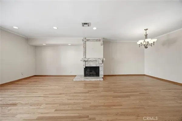 a view of a room with a fireplace a ceiling fan and wooden floor