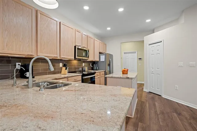 a kitchen with stainless steel appliances a stove a sink a refrigerator white cabinets and wooden floor