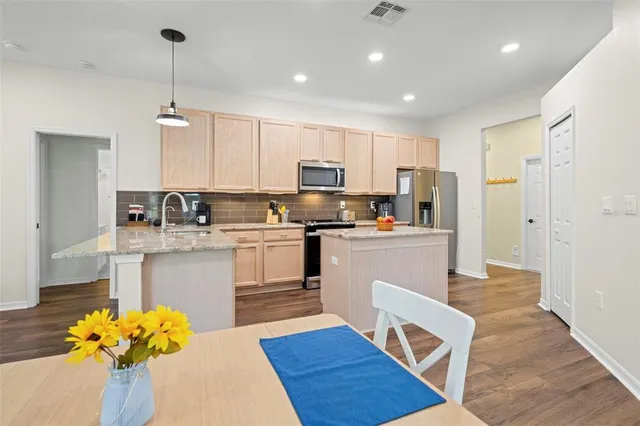 a kitchen with stainless steel appliances granite countertop a refrigerator a stove top oven a sink and dishwasher with wooden floor