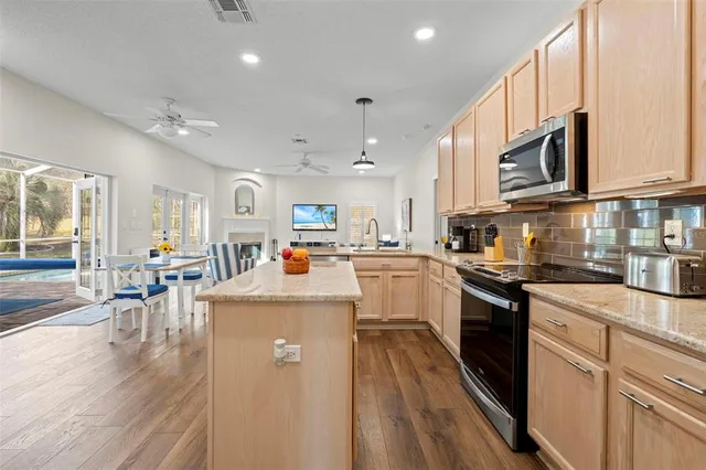 a kitchen with stainless steel appliances granite countertop a refrigerator a stove top oven a sink dishwasher and white cabinets with wooden floor