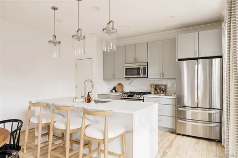 a kitchen with stainless steel appliances granite countertop a refrigerator a stove a sink dishwasher a dining table and chairs with wooden floor
