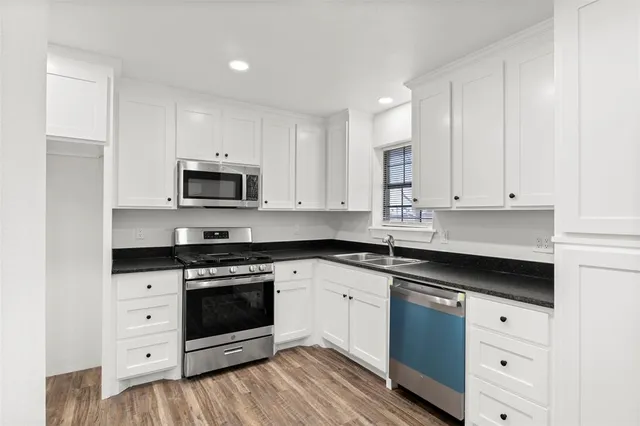 a kitchen with stainless steel appliances granite countertop a stove a sink and a microwave