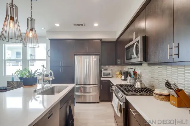 a kitchen with stainless steel appliances kitchen island granite countertop a sink a stove a dining table and chairs with wooden floor