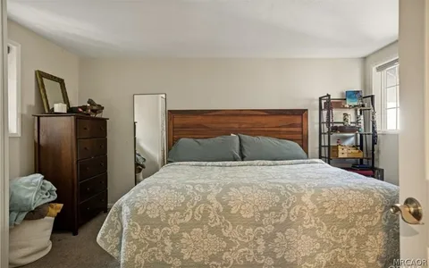 a bed sitting in a bedroom and table chair