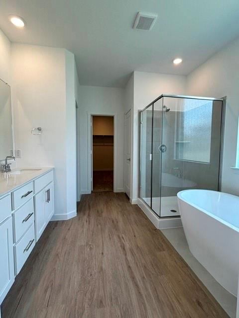 1833 Welsh Road Celina, TX 75009 - Photo 3 of 8 Spacious bathroom featuring a freestanding tub, glass-enclosed shower, dual vanity with white cabinetry, and wood-finish flooring