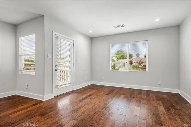 an empty room with wooden floor and window